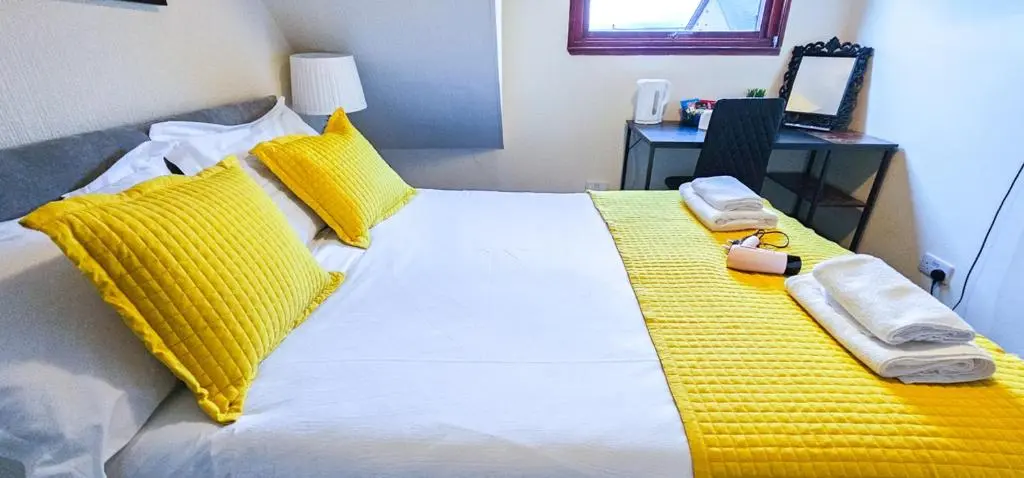 a bedroom with a bed with yellow pillows and a phone at mySTAYINN Telford Guest House in Inverness
