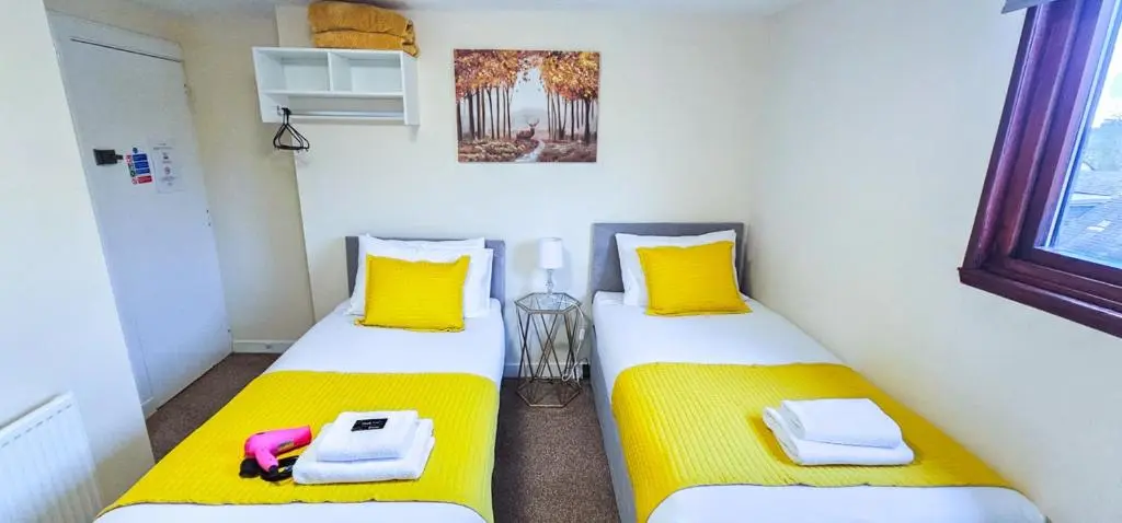 two beds in a room with yellow and white at mySTAYINN Telford Guest House in Inverness