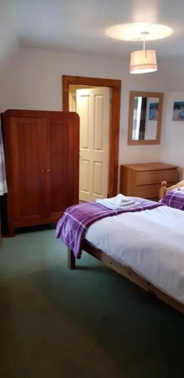 a bedroom with a bed and a wooden dresser at Ness City Apartment in Inverness