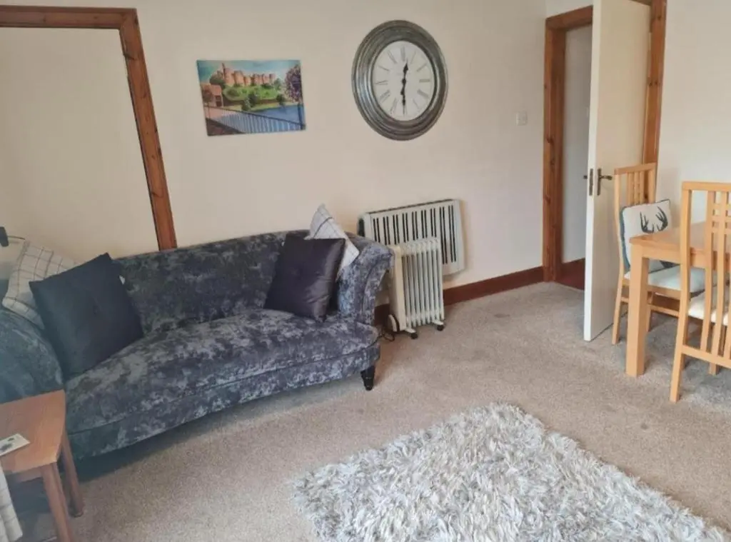 a living room with a couch and a clock on the wall at Ness City Apartment in Inverness