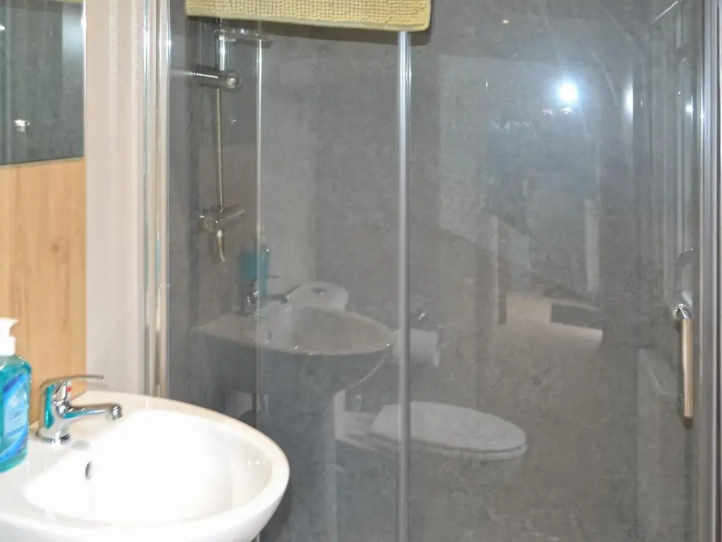a bathroom with a glass shower with a sink and a toilet at The Finch in Dyke