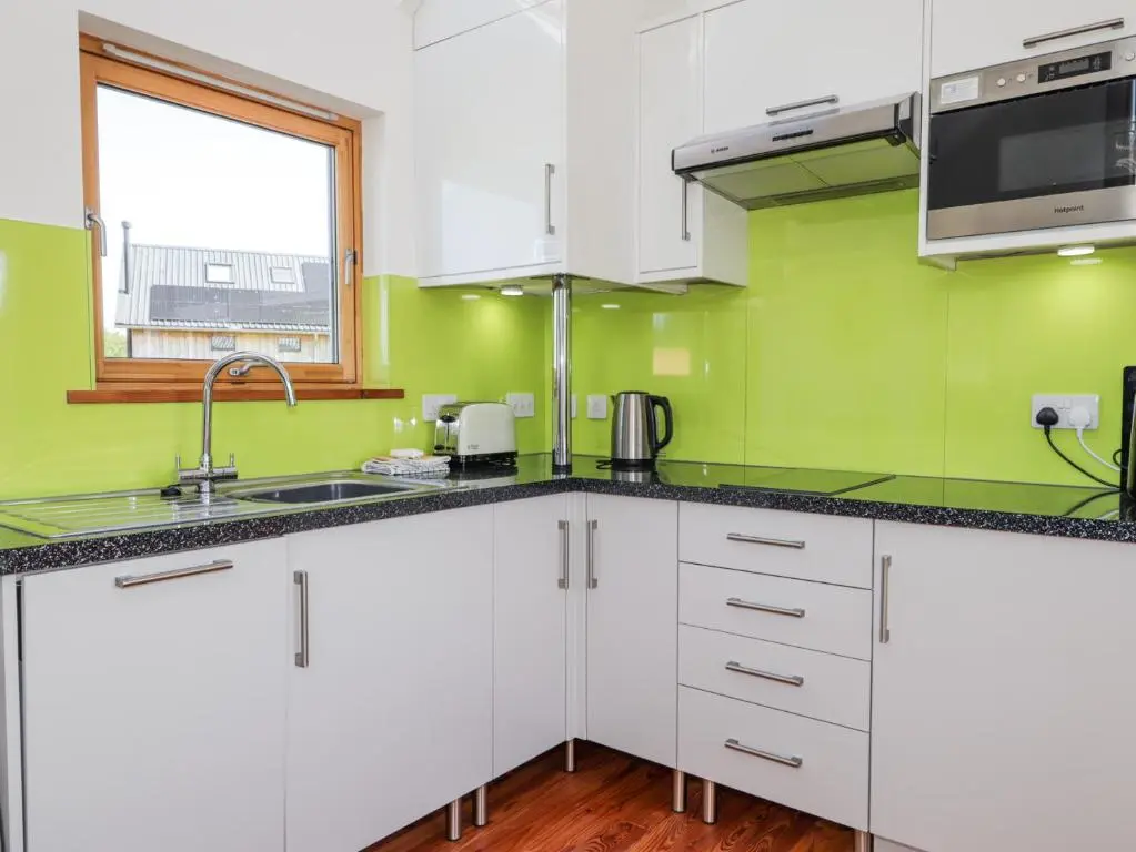 a kitchen with white cabinets and green walls at Easter Blervie in Forres