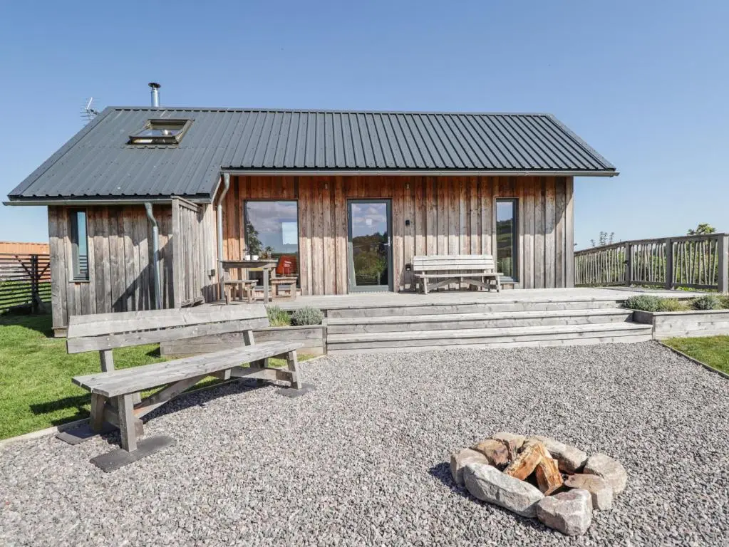 a small wooden cabin with a picnic table and a fire place at Easter Blervie in Forres