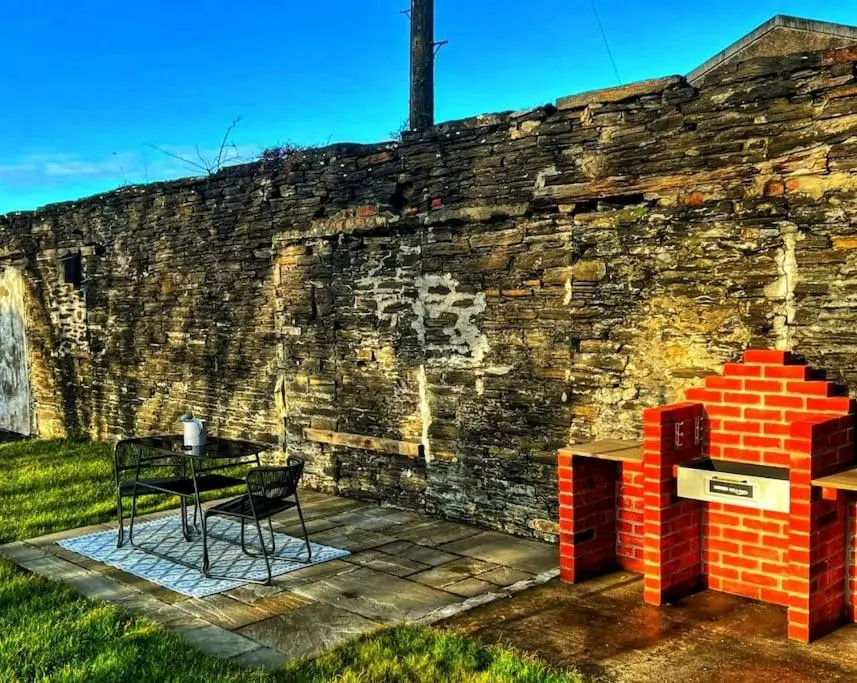 a table and chairs next to a brick wall at GWR Dickson's House, NC500, Wick in Wick