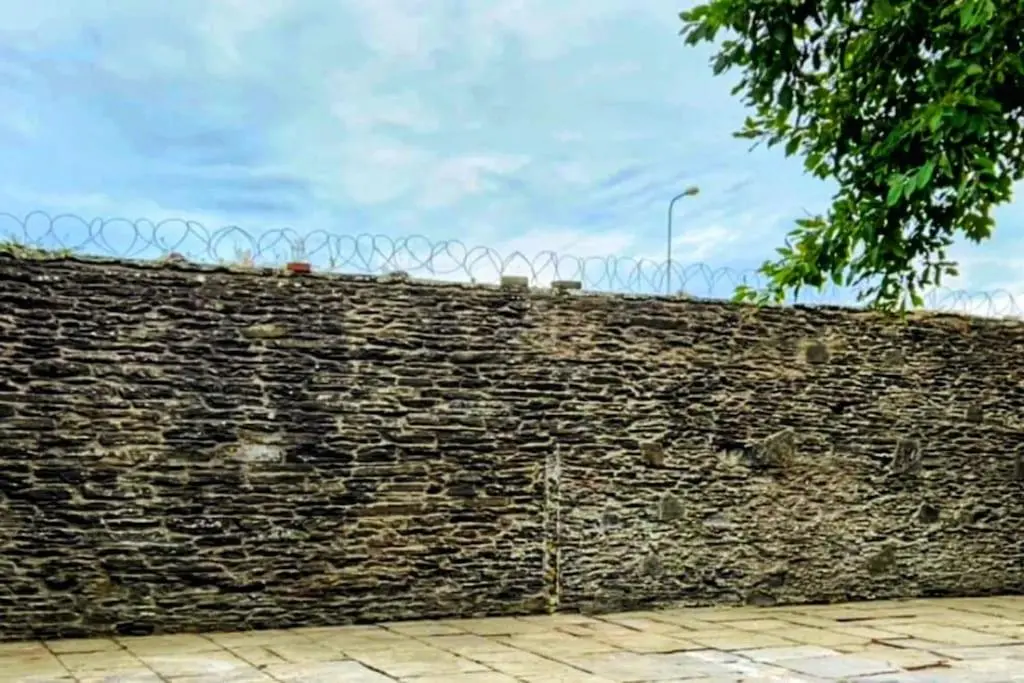 a brick wall with a barbed wire fence at GWR Dickson's House, NC500, Wick in Wick