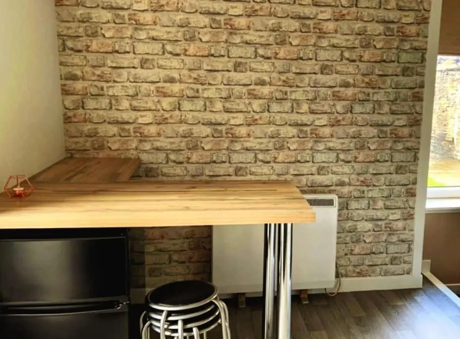 a kitchen with a brick wall and a table and stools at GWR Dickson's House, NC500, Wick in Wick