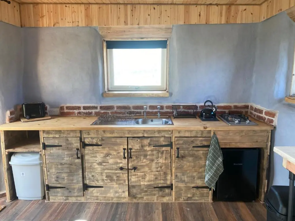 a kitchen with a counter with a sink and a window at Primrose Straw Bale Cabin