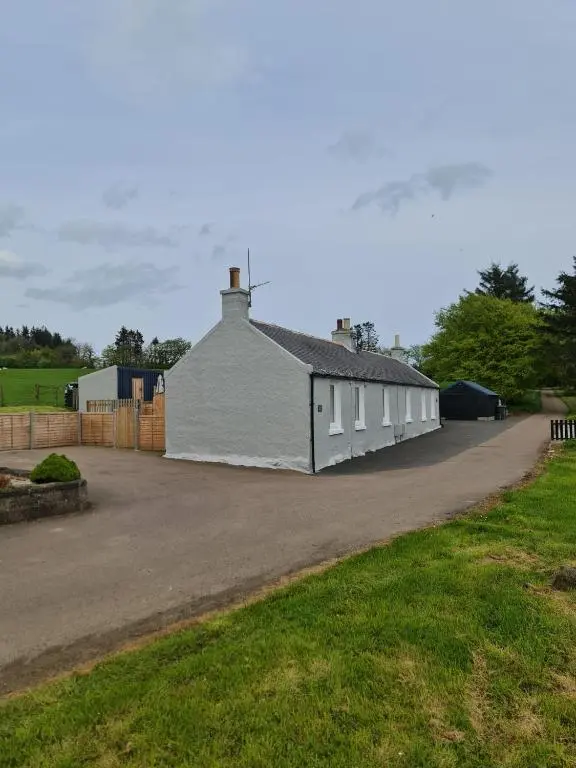 a white building on the side of a road at Bruxie Holiday Cottages - River Cottage in Maud