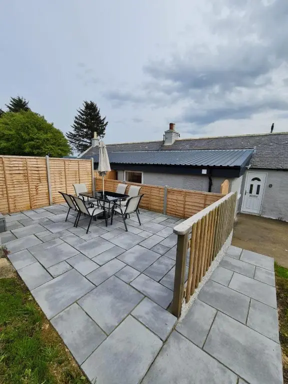 a patio with a table and chairs and a fence at Bruxie Holiday Cottages - River Cottage in Maud
