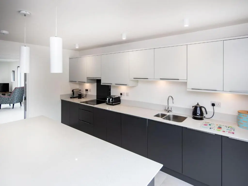 a kitchen with black cabinets and white appliances at Caledonia View in Aviemore