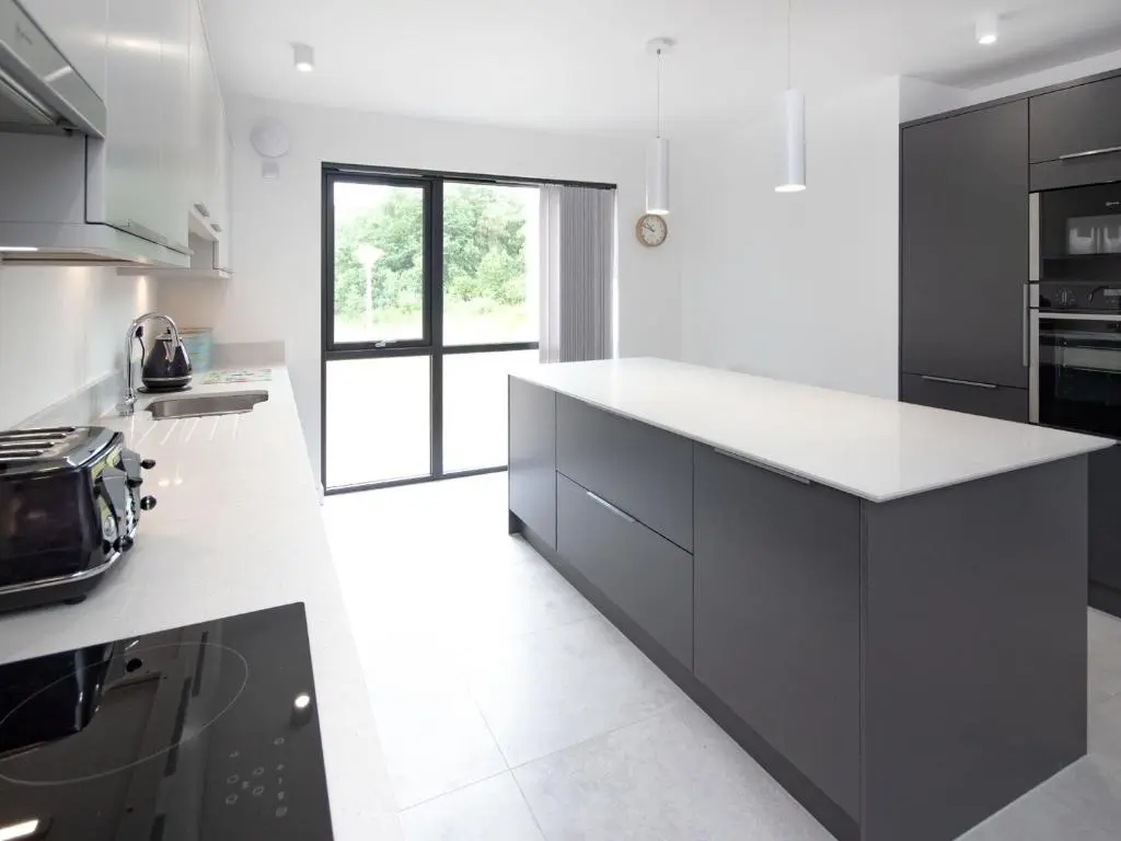 a kitchen with black cabinets and white counter tops at Caledonia View in Aviemore