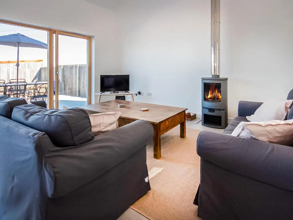 a living room with a couch and a table with a fireplace at Y Bwthyn in Culbokie