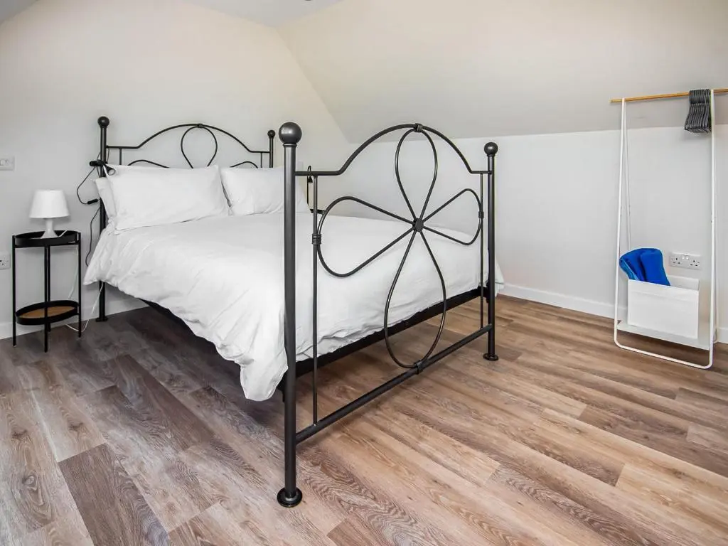 a bedroom with a metal bed with white sheets at Y Bwthyn in Culbokie