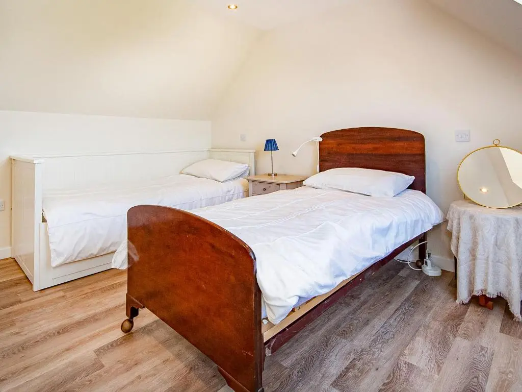 a bedroom with two beds and a mirror at Y Bwthyn in Culbokie