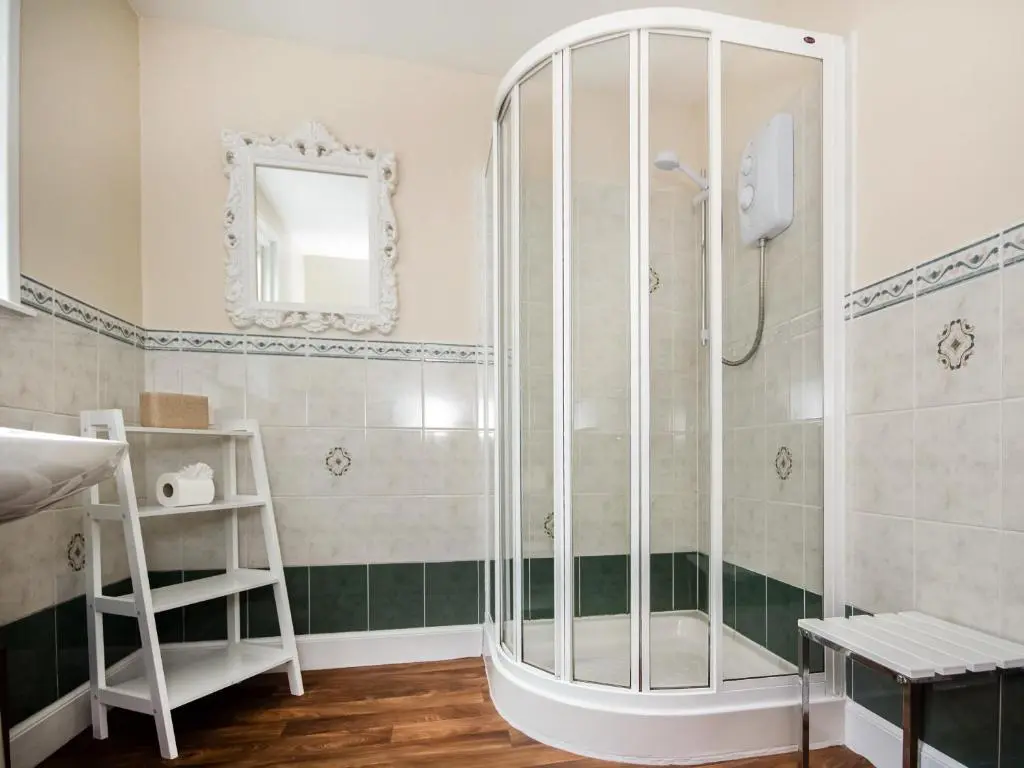 a shower in a bathroom with green and white tiles at Solus Na Madainn in Tain