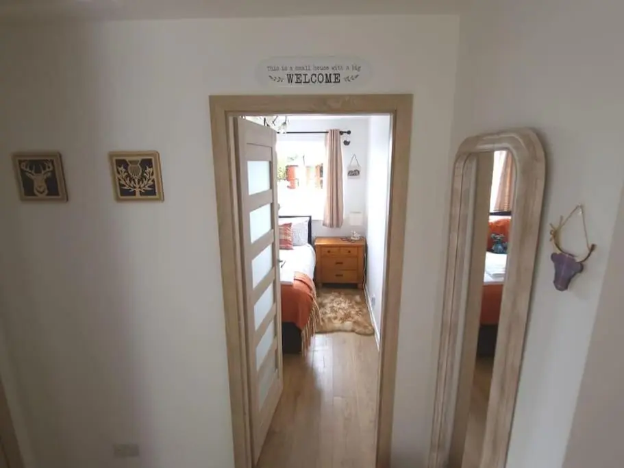 a hallway with a mirror and a bedroom at Northlea-Scottish style cottage in Inverness