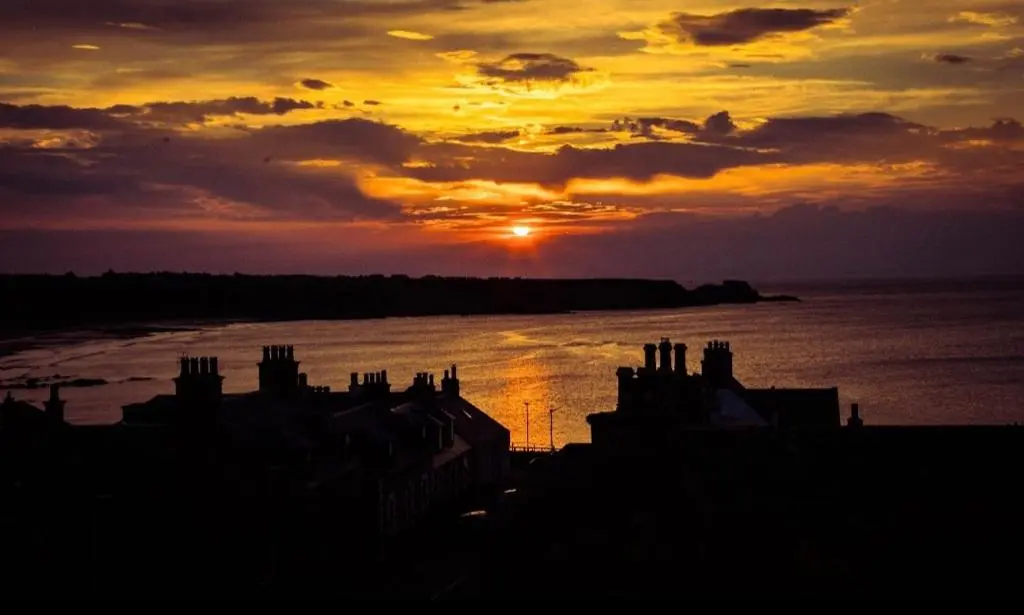 a sunset over a body of water with buildings at Salt View in Cullen