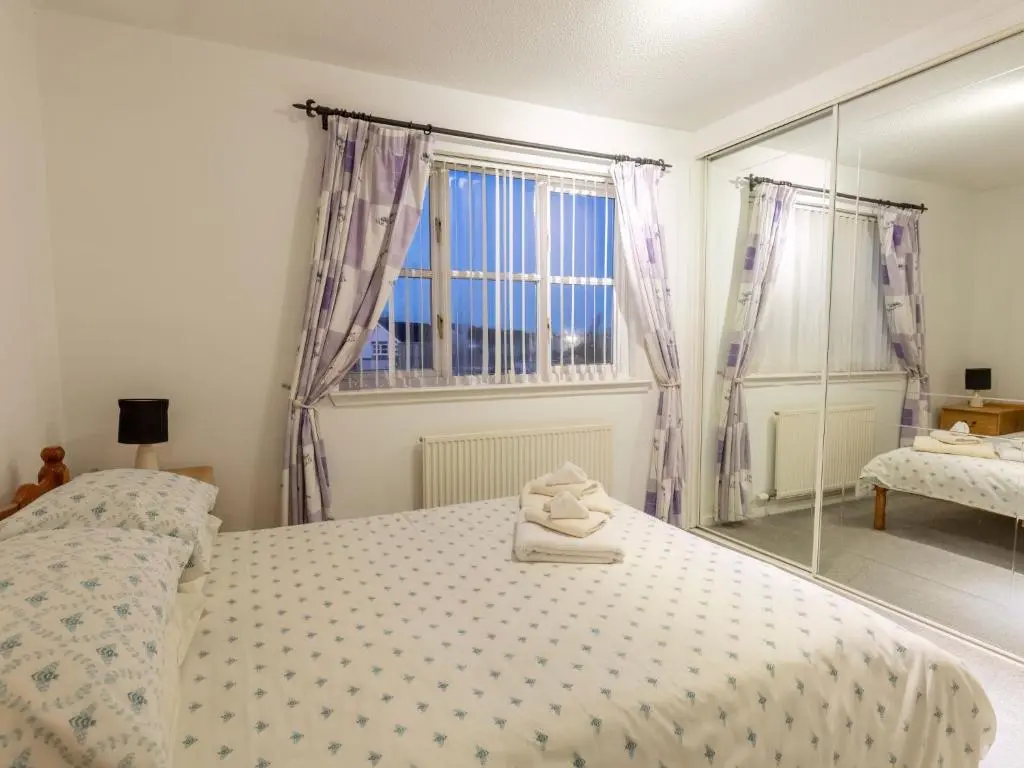 a bedroom with a bed and a window and a mirror at Villa Cedar House by Interhome in Inverness