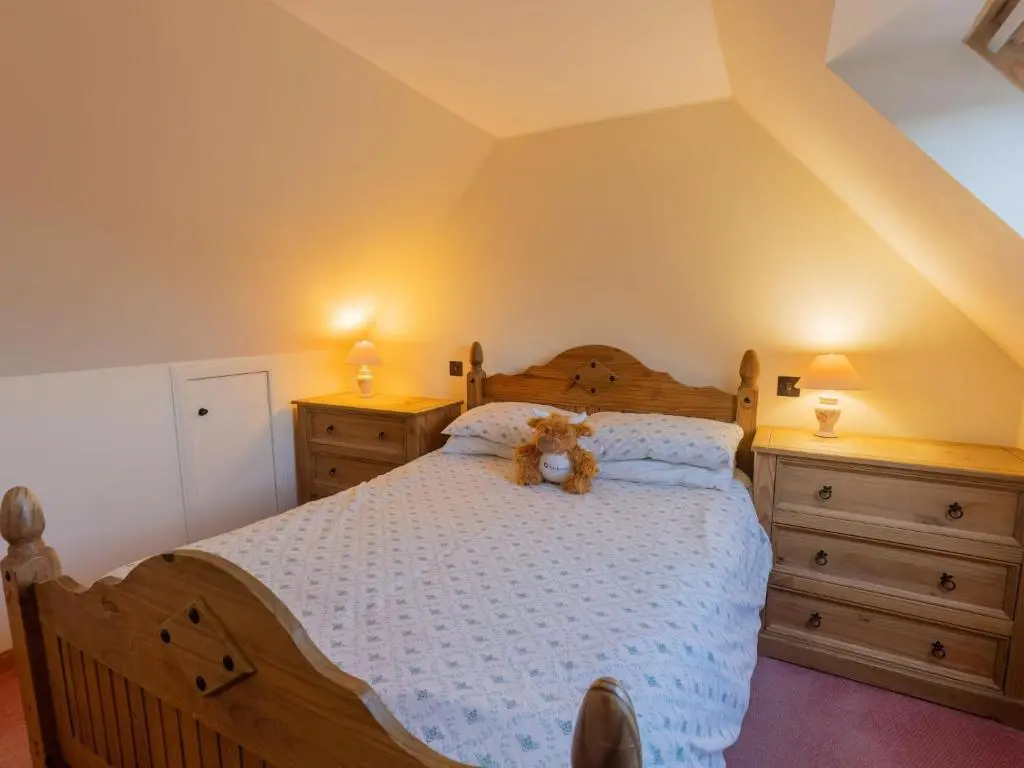 a teddy bear sitting on a bed in a bedroom at Holiday Home Lodge Road by Interhome in Inverness