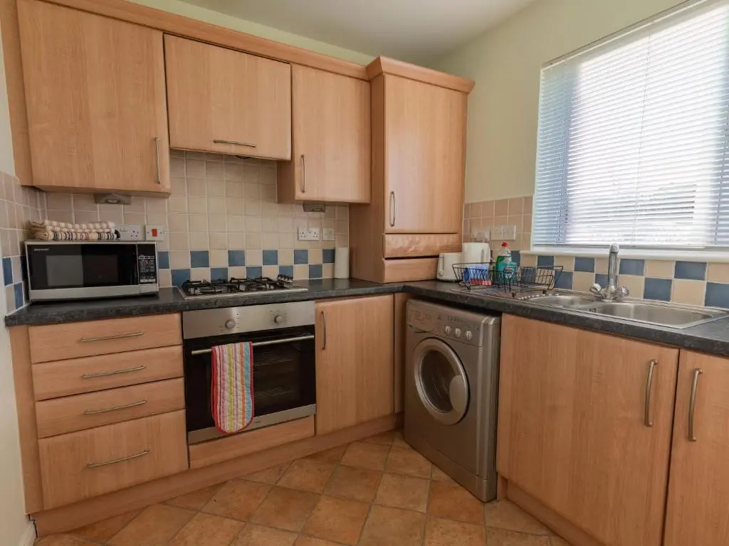 a kitchen with wooden cabinets and a washer and dryer at Apartment Ash House by Interhome in Inverness