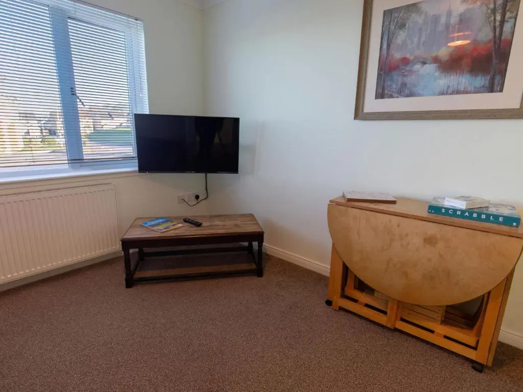 a room with a table and a tv and a table with a coffee table at Apartment Ash House by Interhome in Inverness