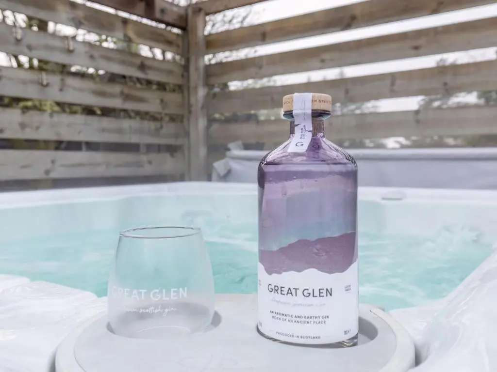 a bottle and a glass sitting on top of a table at Chalet Lothlorien Lodge 4 by Interhome in Spean Bridge