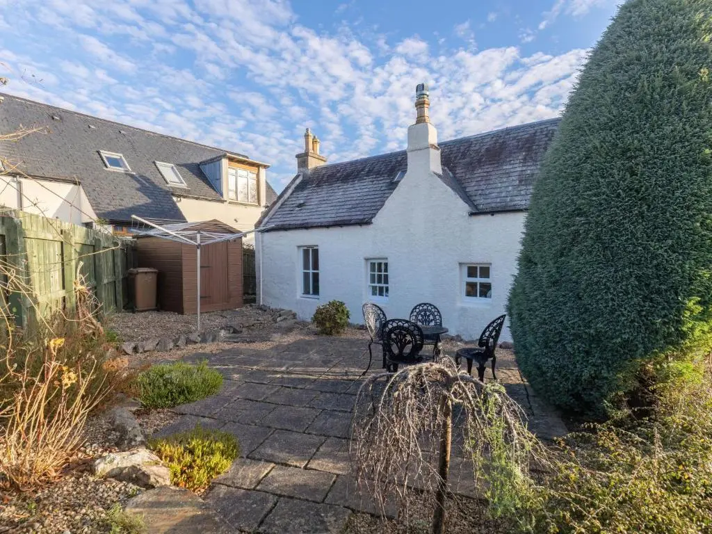 a white house with two benches in front of it at Holiday Home Old Lodge by Interhome in Inverness