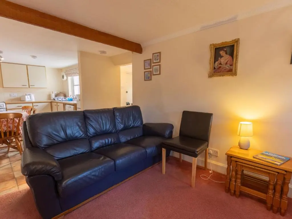 a living room with a leather couch and a chair at Holiday Home Old Lodge by Interhome in Inverness