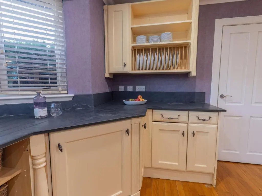 a kitchen with white cabinets and a black counter top at Villa Evergreen House by Interhome in Inverness