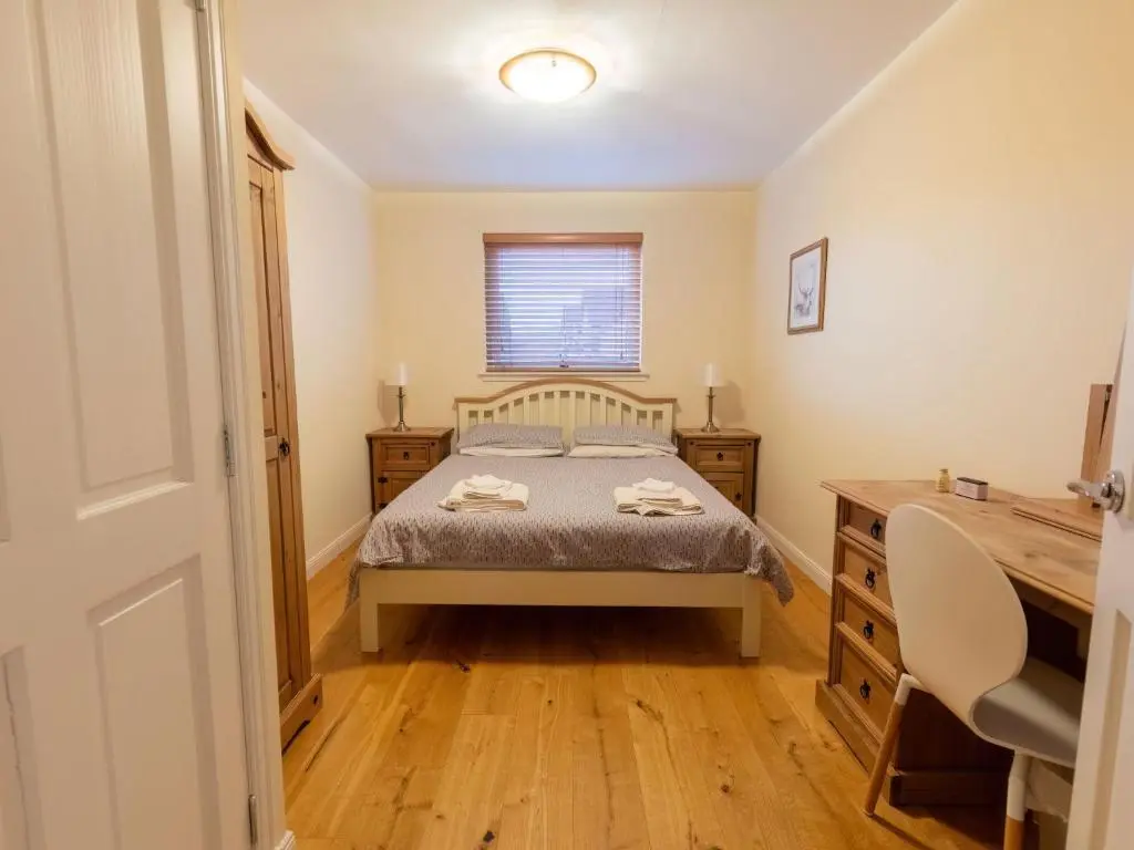 a bedroom with a bed and a wooden desk at Villa Evergreen House by Interhome in Inverness