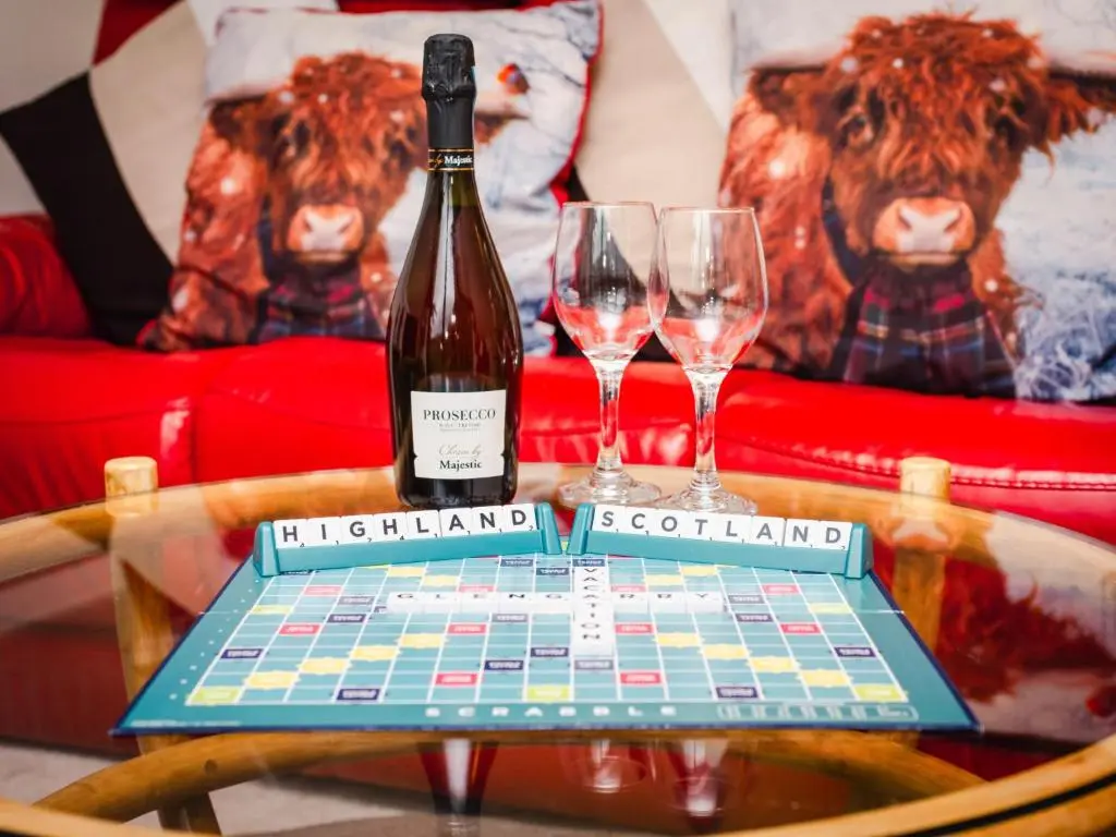 a bottle of wine sitting on a table with two wine glasses at Chalet Rivendell by Interhome in Spean Bridge