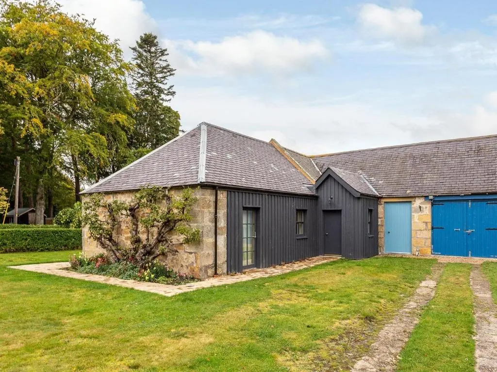an old stone building with a blue garage at 1 Bed in Forres 78430 in Forres