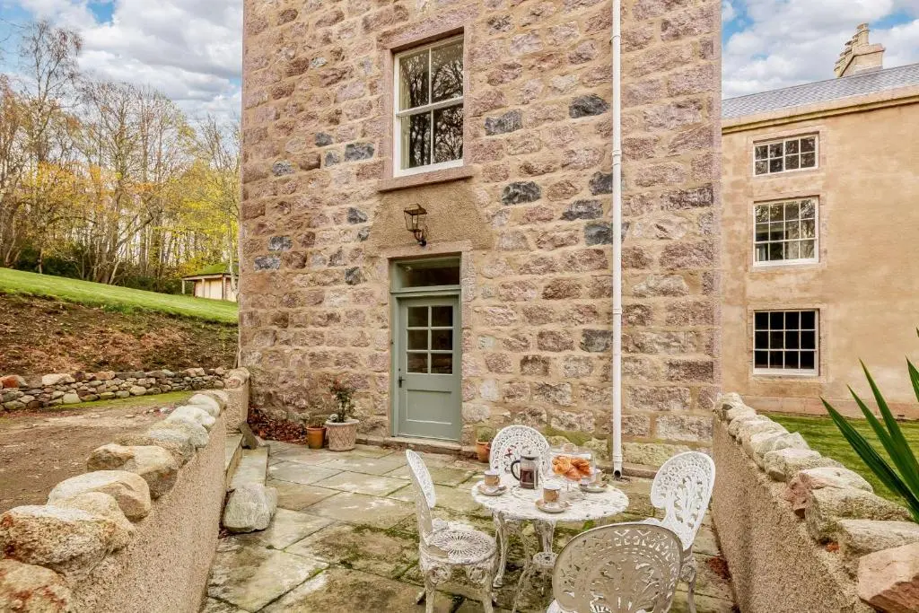 a table and chairs in front of a stone building at Manar House Ground Floor Luxury Apartment in Inverurie