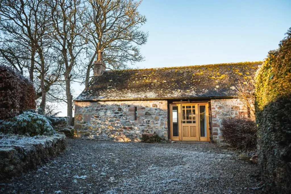 a stone house with a door in the snow at Kinkell Cottage in Dingwall