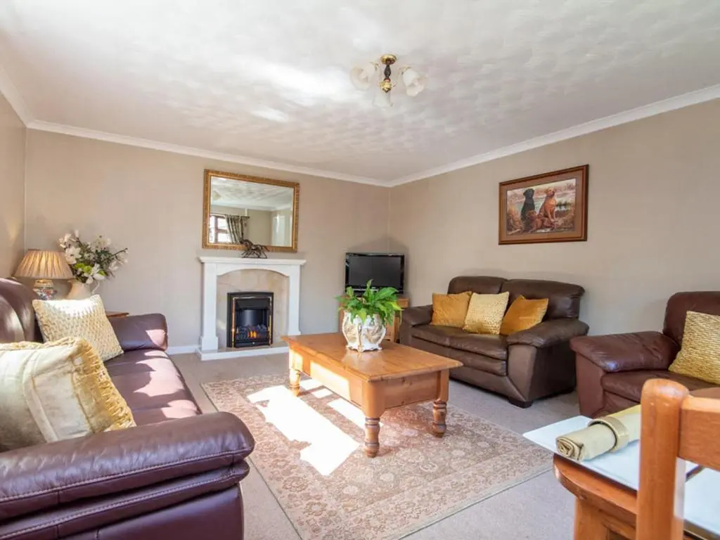 a living room with leather furniture and a fireplace at Black Rock Cottage in Culbokie