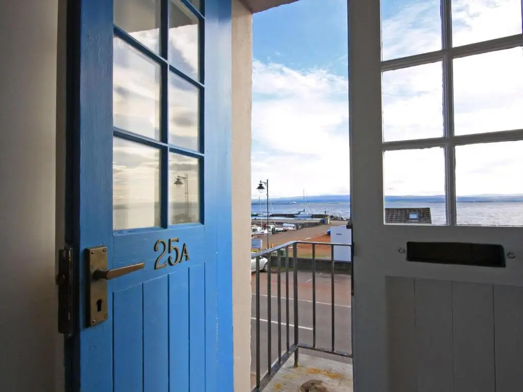 a door to a balcony with a view of the beach at The Old Chandlery in Avoch