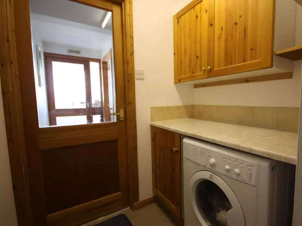 a laundry room with a washing machine and a door at The Old Chandlery in Avoch