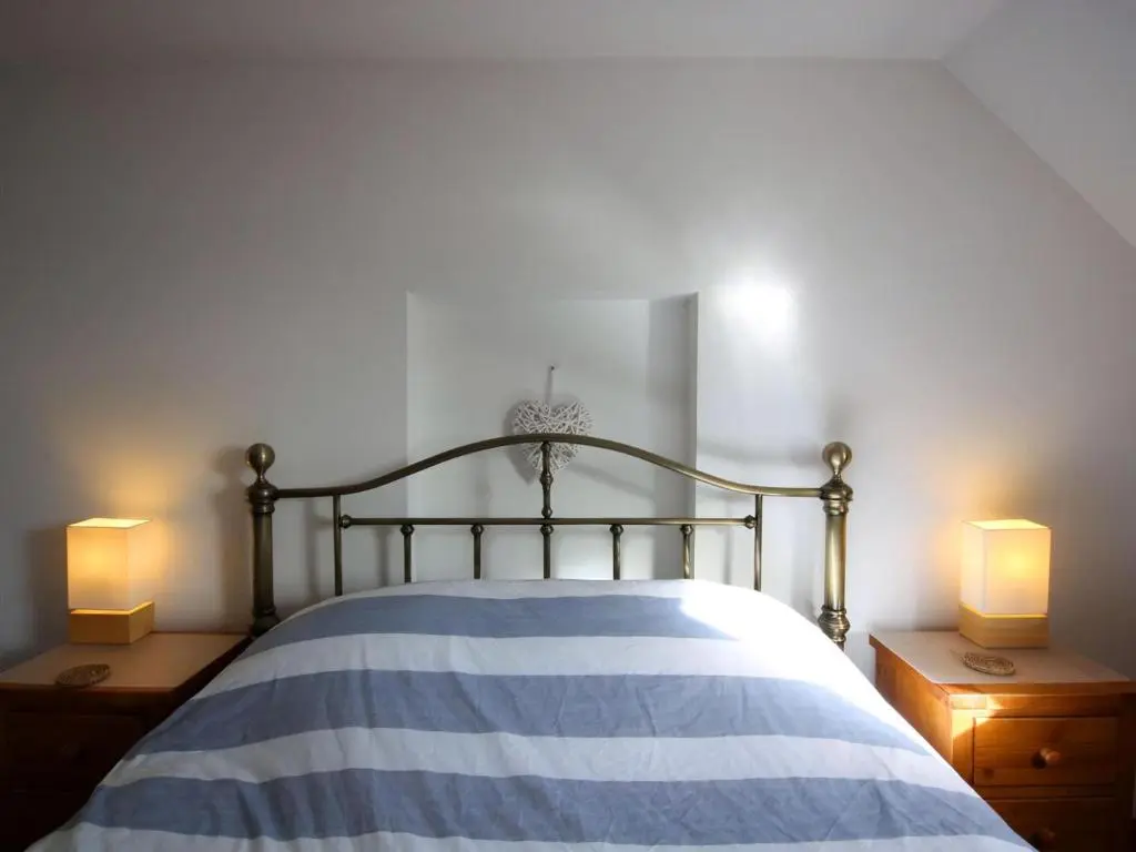 a bedroom with a bed with two lamps on two dressers at The Old Chandlery in Avoch