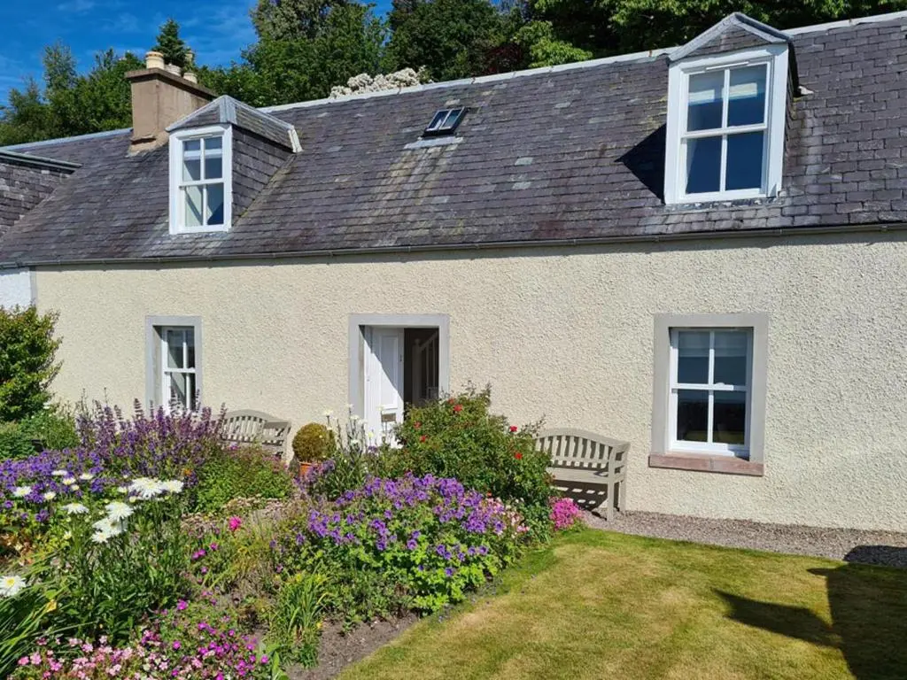 a white house with a bench in a garden at Braefoot in Fortrose