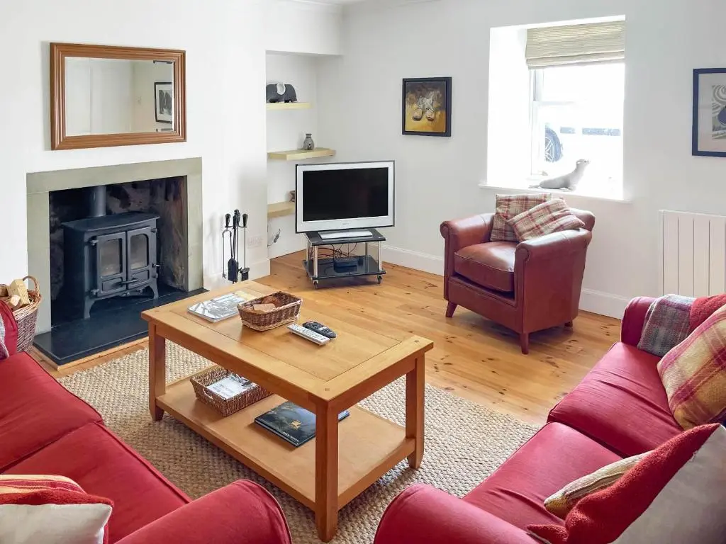 a living room with a couch and a table and a tv at Braefoot in Fortrose