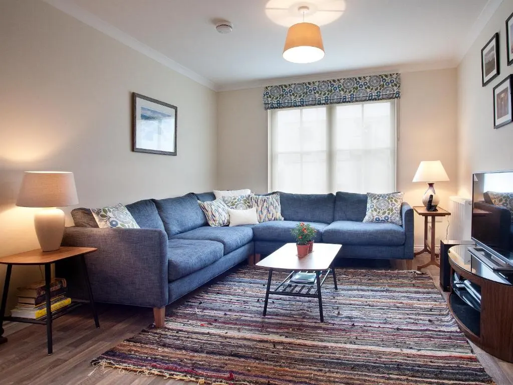 a living room with a blue couch and a tv at Mackay Road - Uk7451 in Dornoch