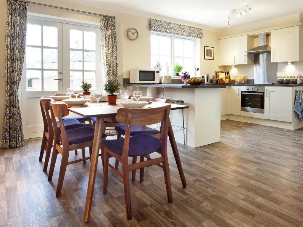a kitchen with a wooden table with chairs and a table and a kitchen with at Mackay Road - Uk7451 in Dornoch
