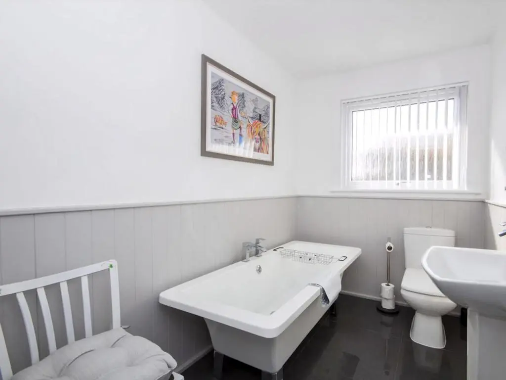 a white bathroom with a sink and a toilet at Raasay in Dornoch