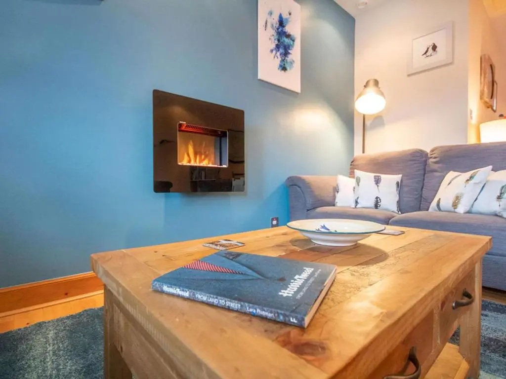 a living room with a table and a fireplace at Bird's Eye View in Dornoch