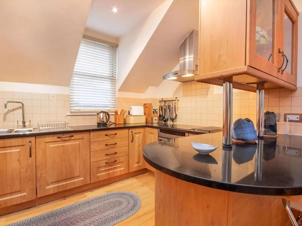 a kitchen with wooden cabinets and a black counter top at Bird's Eye View in Dornoch