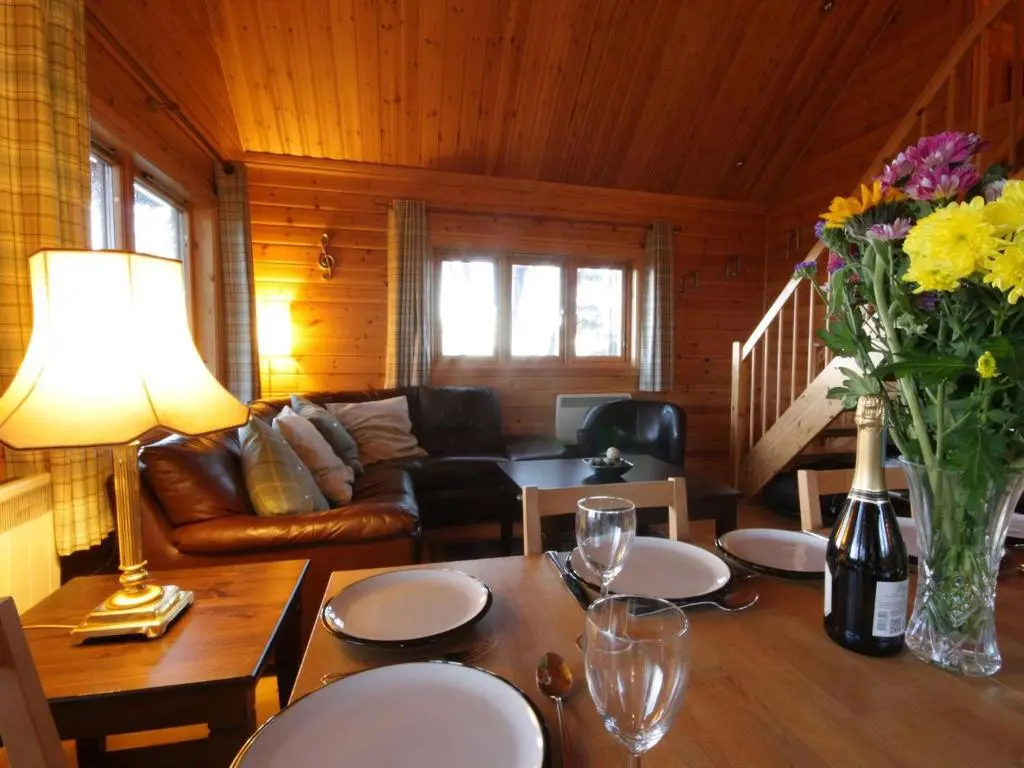 a living room with a table with a vase of flowers at Taigh Fiodha in Balintore