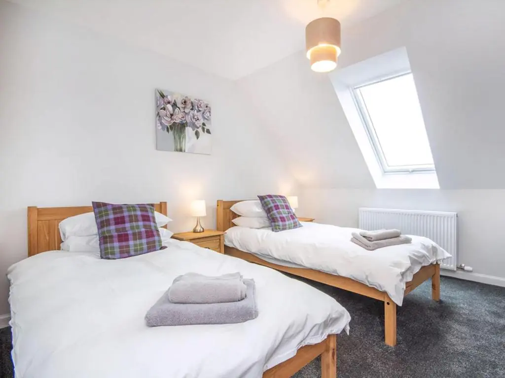 two twin beds in a room with a window at On The Beach-Uk7465 in Balintore