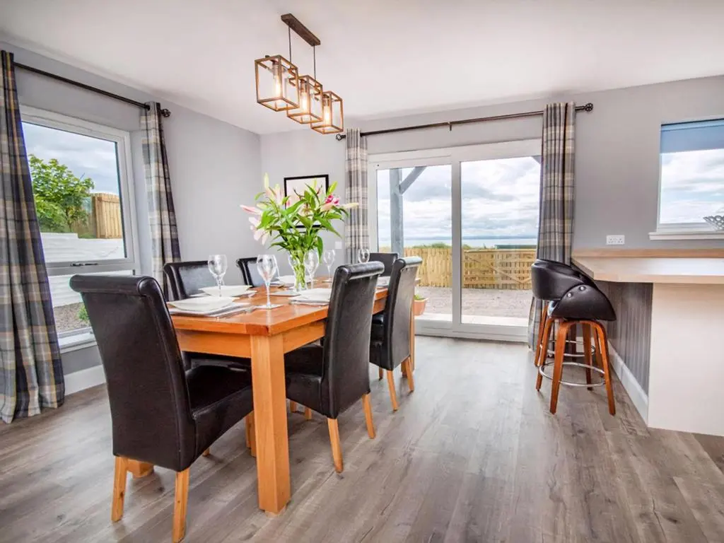 a dining room with a wooden table and black chairs at On The Beach-Uk7465 in Balintore