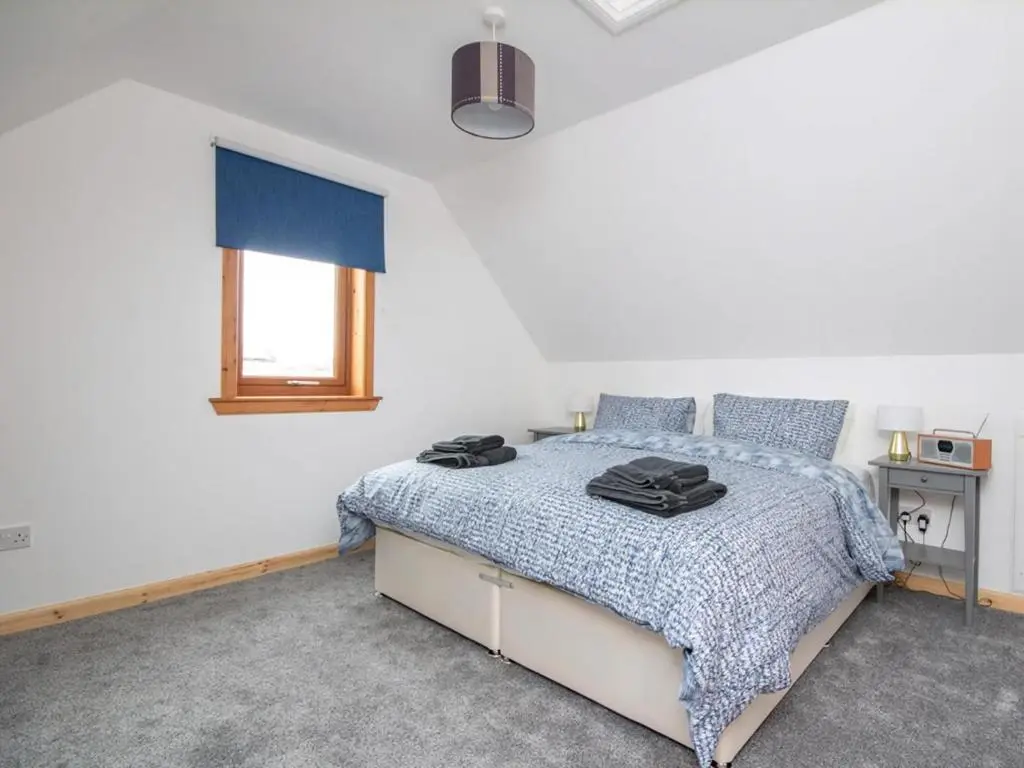 a bedroom with a bed with a blue comforter at Lower Whinhill in Evelix