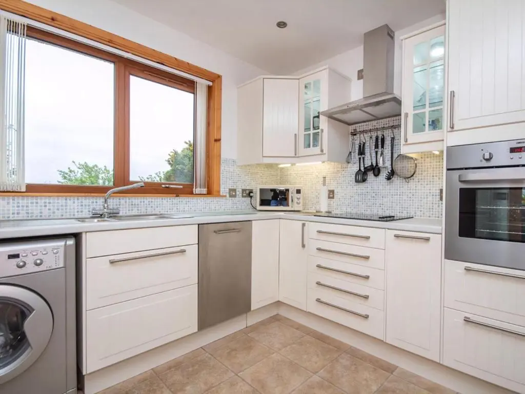 a kitchen with white cabinets and a dishwasher at Lower Whinhill in Evelix